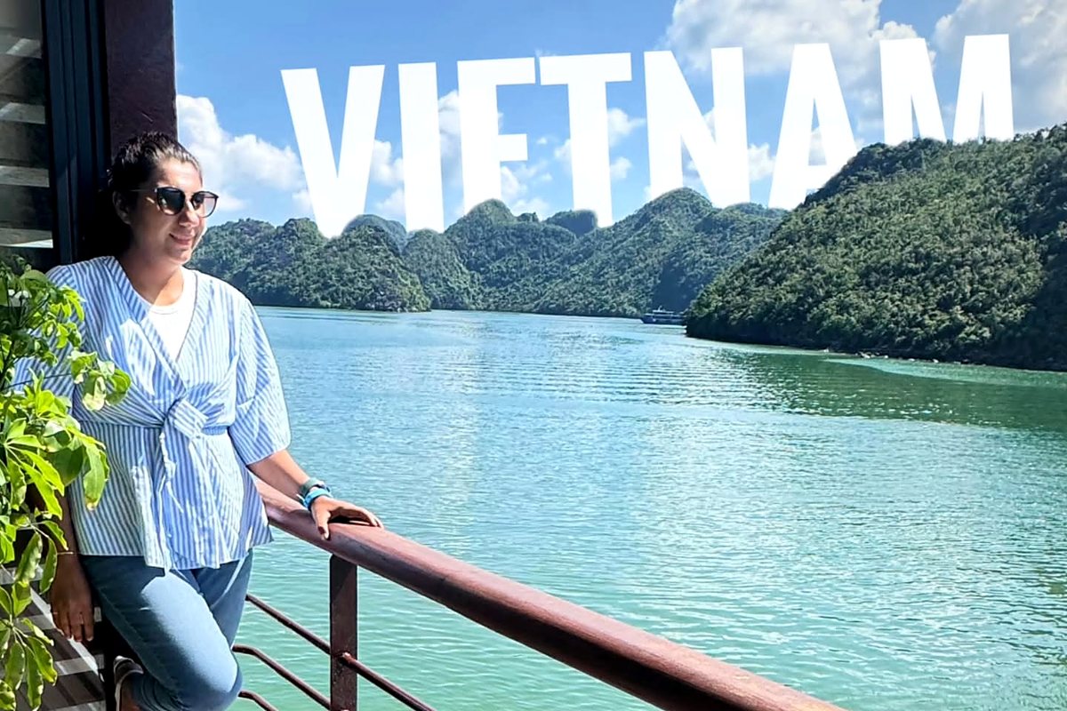 Saudamini on a cruise deck in Ha Long Bay, VIETNAM written across the sky above the limestone islands
