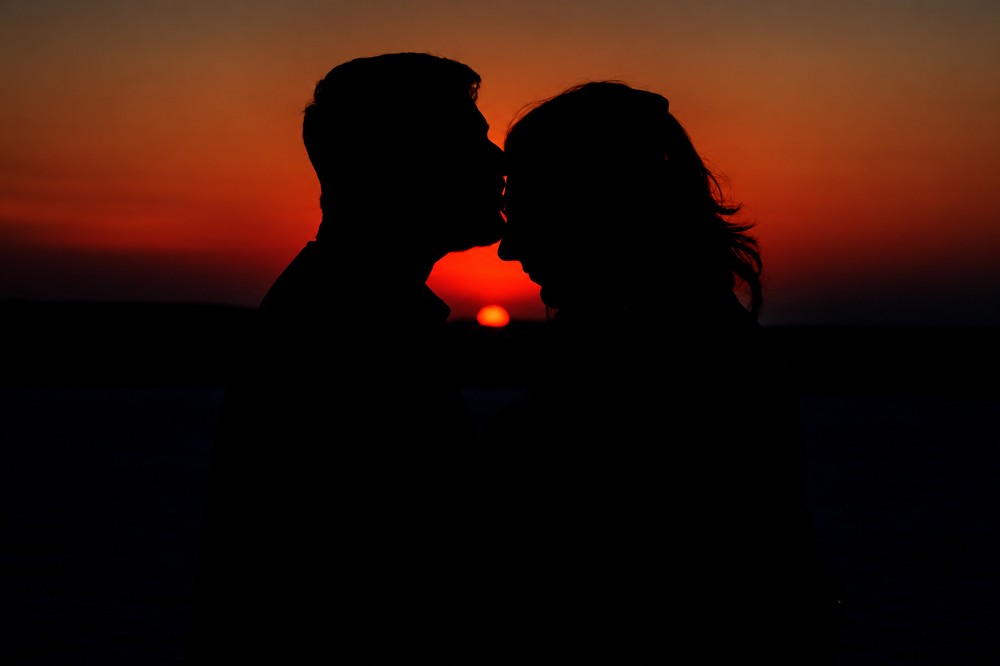 Saudamini and Shriram in silhouette against a deep red sunset