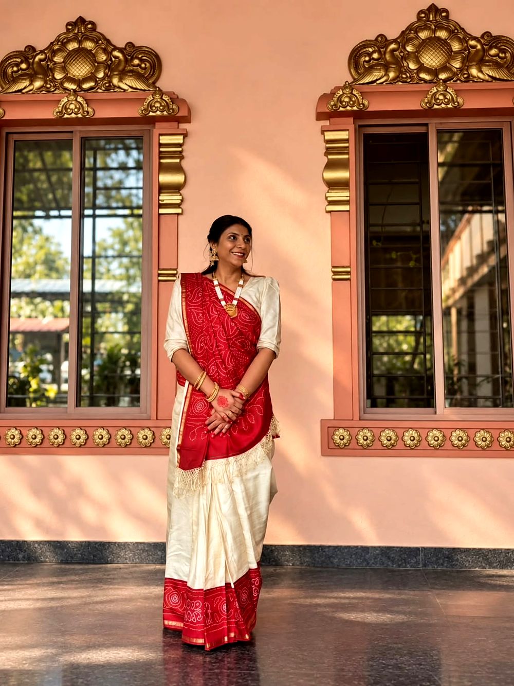 In a red-and-white saree in a sunlit courtyard