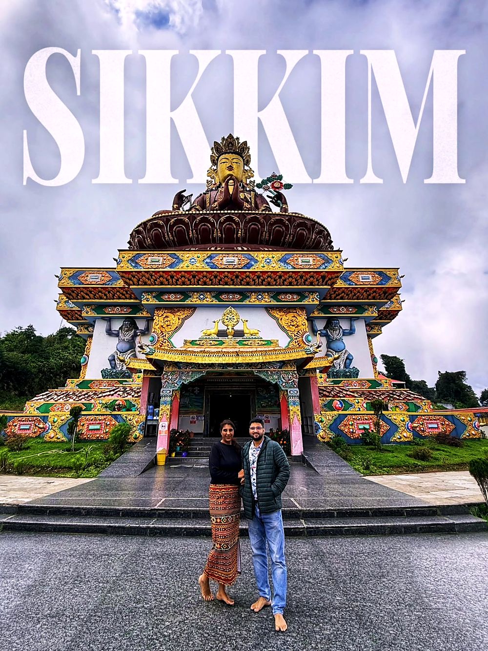 Saudamini and Shriram in front of a monastery with a giant Buddha
