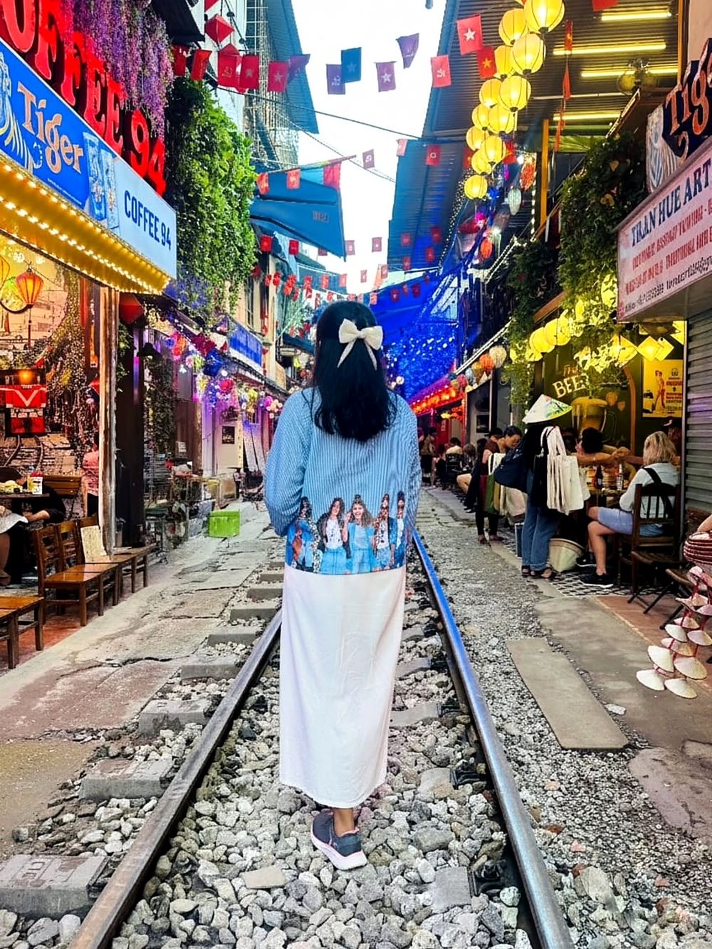 Walking along the railway tracks of Hanoi's Train Street, lined with cafés and lanterns